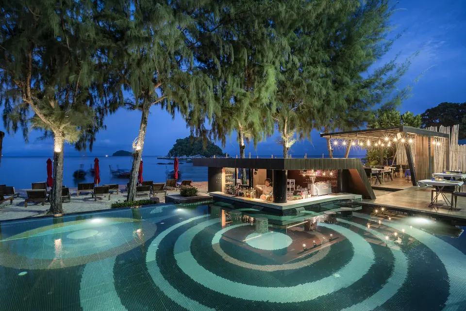 Resort swimmingpool med liggestole og bar i skumringen