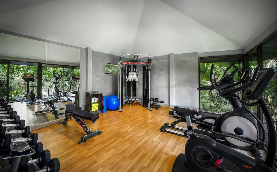 Fitnessrum med håndvægte, træningsbænk og konditionsmaskiner.