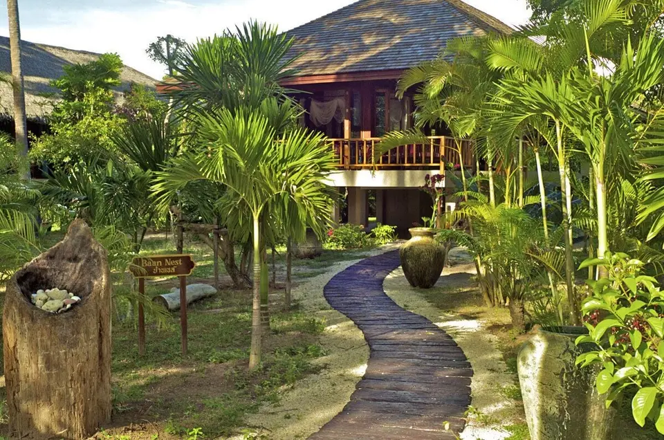 Villa med træbalkon og havesti mellem palmer på Koh Jum Beach Villas.