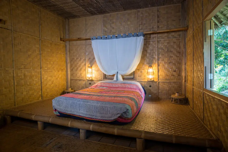 Naturligt designet værelse med bambusvægge og seng på Lanjia Lodge i Chang Rai.
