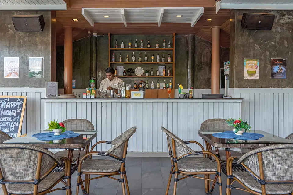 Baren på Orchidacea Resort med caféborde og bartender bag disken