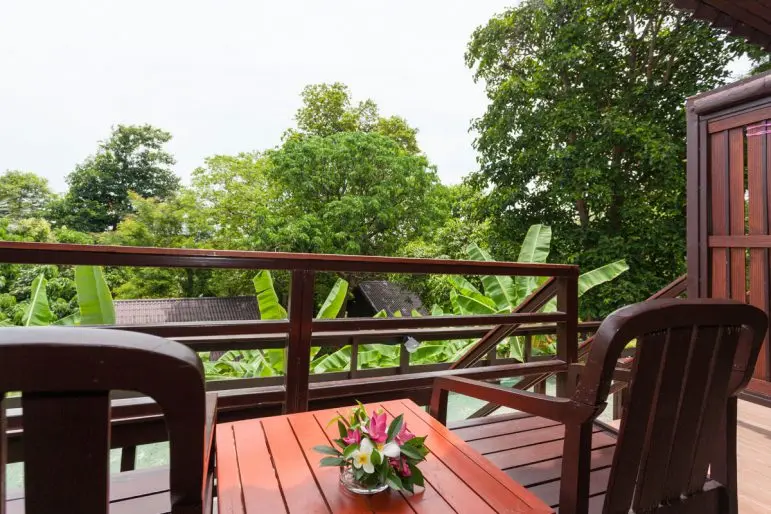 Overdækket balkon med træbord, stole og udsigt til grønne omgivelser på Phi Phi Natural Resort.