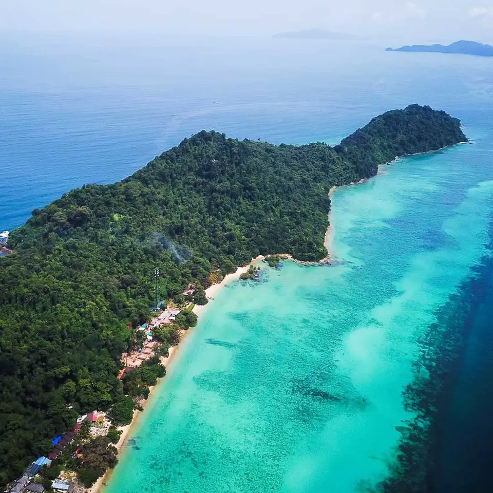 Luftfoto af Koh Kradans skovklædte kyst og turkisblå hav.