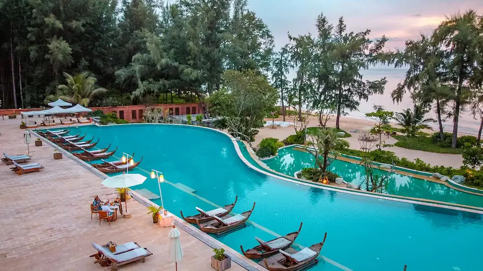 Tropisk resort med swimmingpool og lounge stole