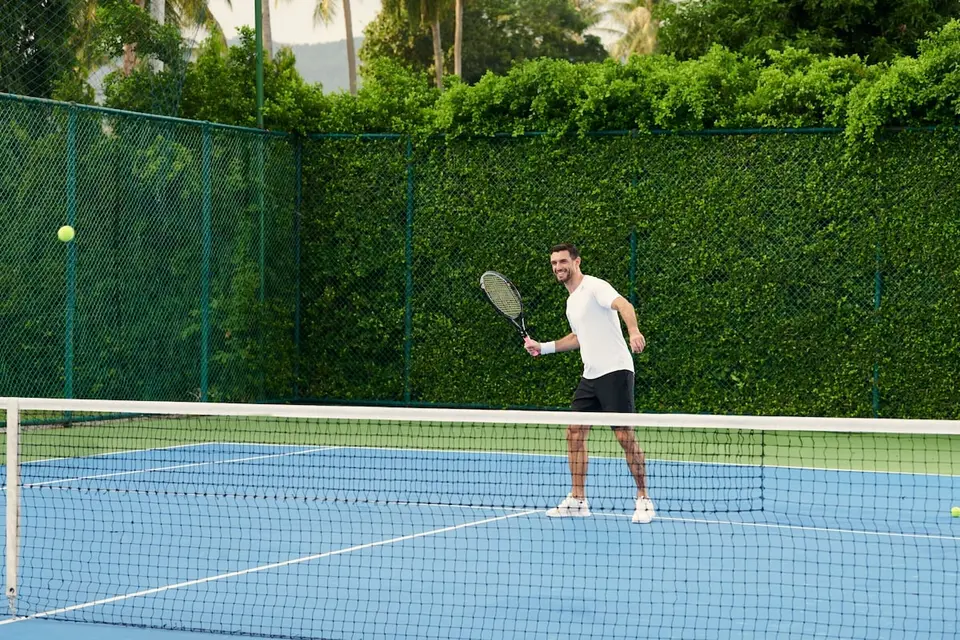 Mand spiller tennis på Santiburi tennisbane i Koh Samui