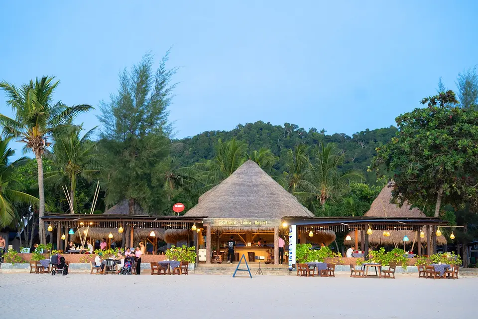 Beachfront restaurant på Southern Lanta Resort med spiseborde arrangeret på sandede kyster.