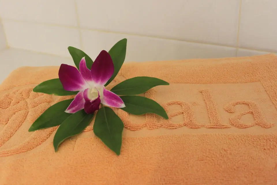 Orange håndklæde med Sudala-navn, pyntet med en lilla blomst.