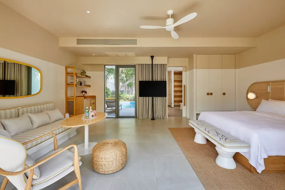 Værelse med dobbeltseng, sofa, tv og udgang mod pool på The Standard Hua Hin.