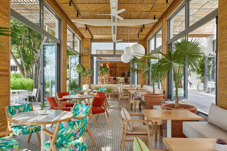 Autentisk Hua Hin restaurant med træborde og stole, omgivet af grønne stueplanter.