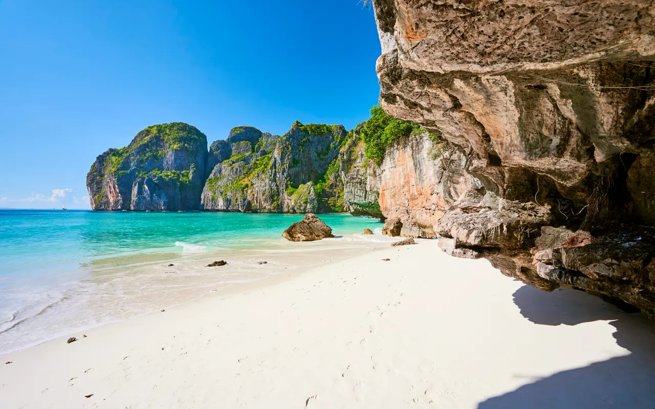 Solrig strand med hvide klipper og gyldent sand i Thailand