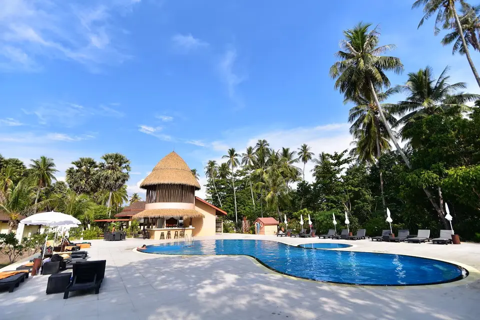Swimmingpool med liggestole, parasoller og strandbar omgivet af palmer på Sivalai Beach Resort under blå himmel.