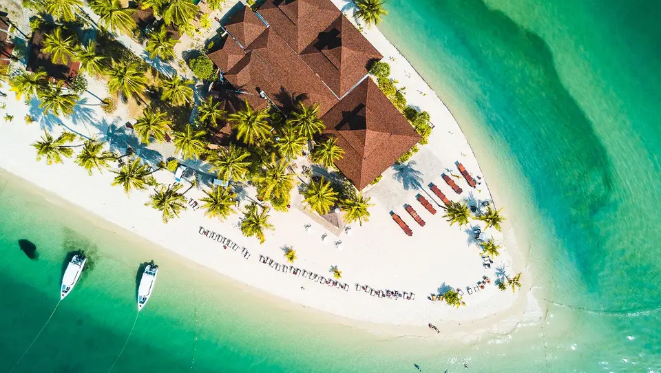 Sivalai Beach Resort med palmer, røde tage og både i det klare turkisblå vand skaber en afslappet ferieidyl.