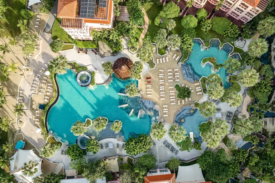 Luksuriøst poolområde omkranset af palmer og frodige haver på Centara Grand Beach Resort Phuket.