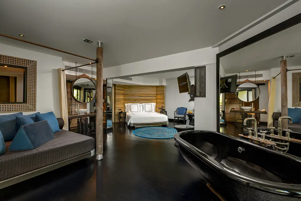 Værelse på The Slate med dobbeltseng, sort fritstående badekar og daybed med blå puder.