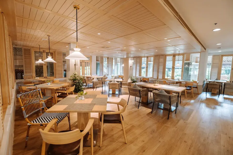 Lys og rummelig restaurant på Khaolak Merlin Resort med træmøbler, grønne planter og hyggelig feriestemning.
