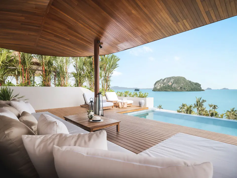 Eksklusivt loungeområde med hvide puder, træterrasse og infinity pool med udsigt til hav og ø ved Anantara Koh Yao Yai.