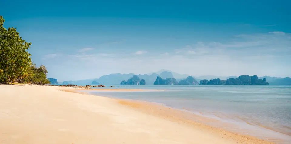 Fredelig, gylden sandstrand med lavt vand og udsigt til små øer nær Anantara Koh Yao Yai Resort i Thailand.