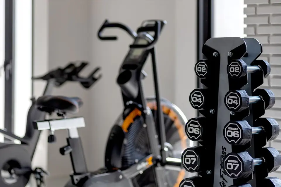 Stativ med håndvægte og motionscykler i fitnessrummet.