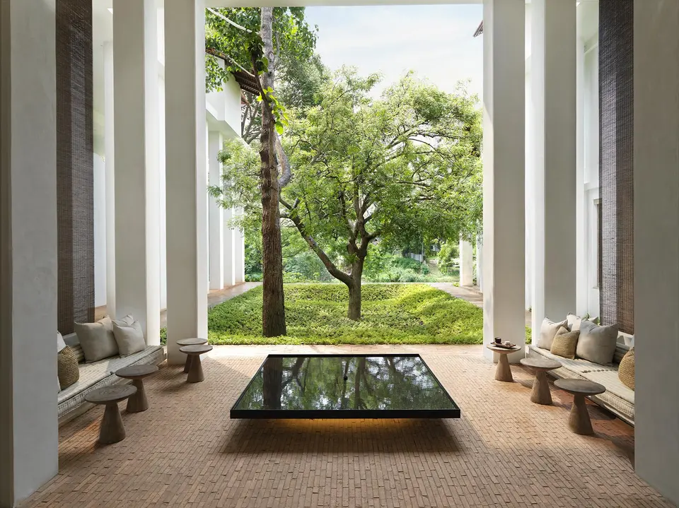 Åben lounge med udsigt til frodig tropisk have og flod, afslappet stemning på Raya Heritage i Chiang Mai.