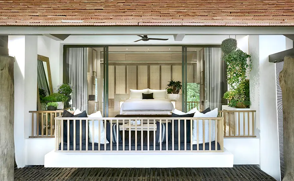 Afslappende terrasse med bløde hynder og udsigt over floden ved Raya Heritage i Chiang Mai, omgivet af grønne planter.