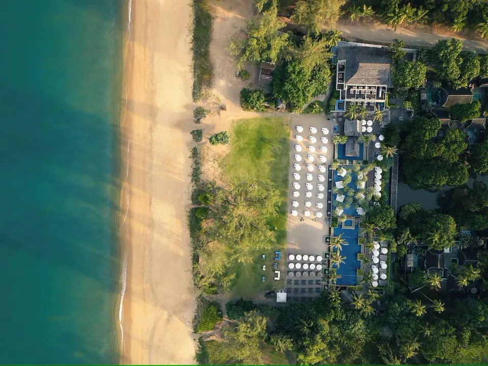 Luksuriøst resort ved strandkanten på Phuket med hvide liggestole, palmer og afslappet atmosfære.