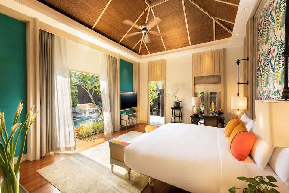 Lyst hotelværelse på Anantara Mai Khao i Phuket med stor seng, farverige puder og adgang til privat have og pool.