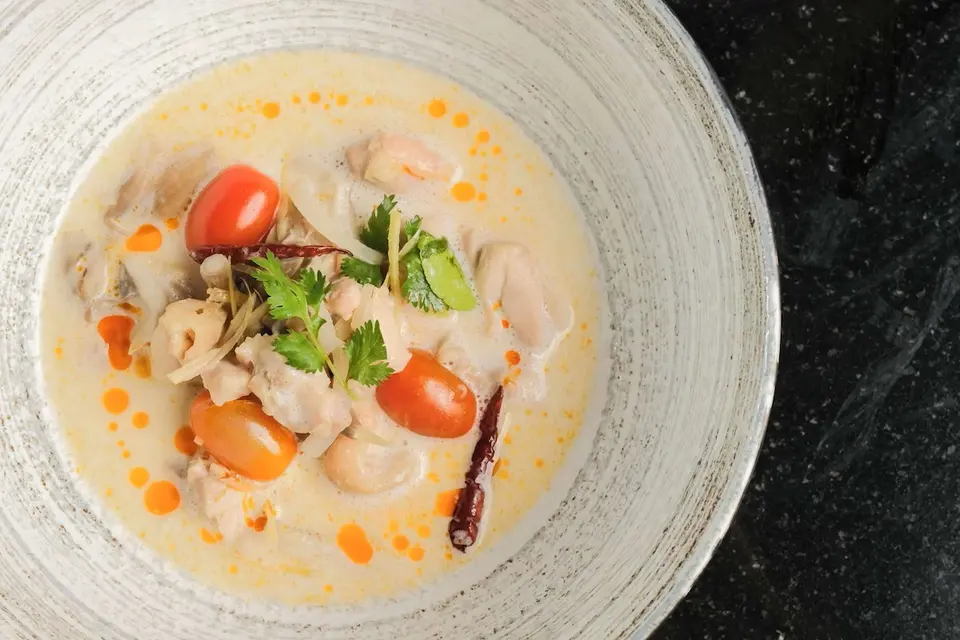Kremet kyllingesuppe med cherrytomater og koriander serveres på Anantara Mai Khao Phuket Villas i afslappede, tropiske omgivelser.