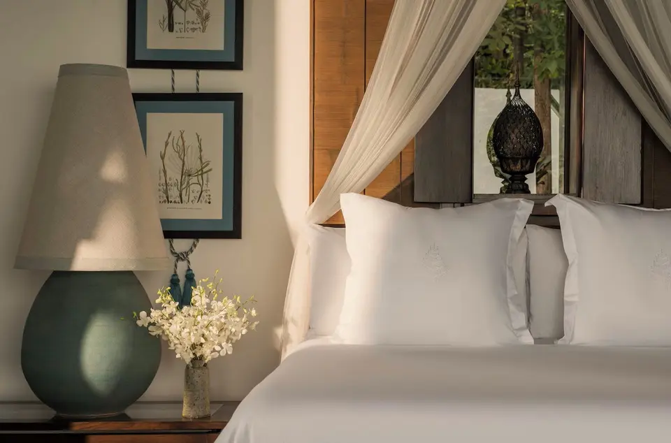Elegant soveværelse med hvide lagner og blomster på natbordet på luksusresort i Koh Samui.