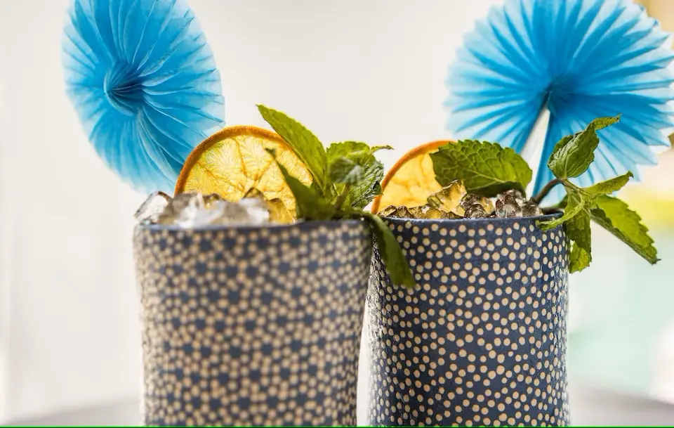 To drinks med knust is, citrus og mynte i blå mønstrede krus.