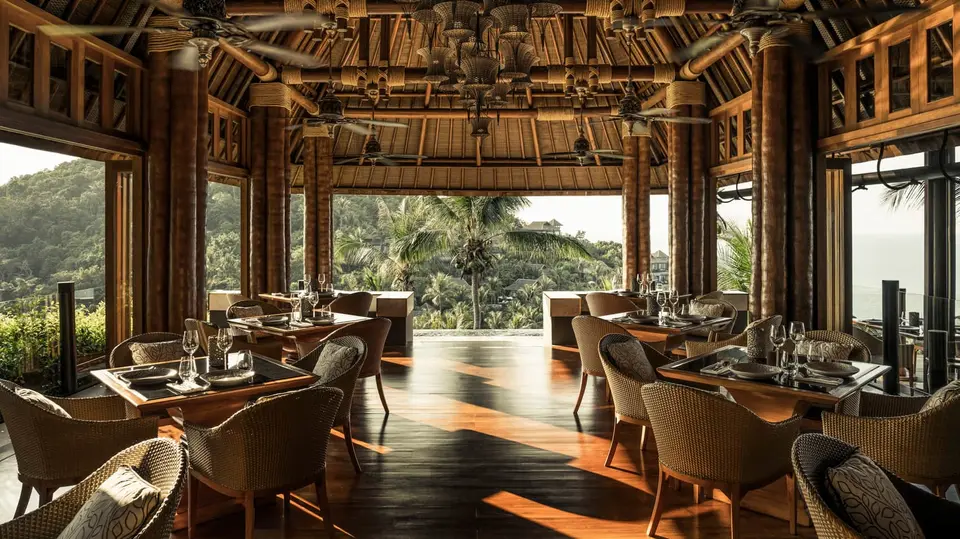 Stemningsfuld open-air restaurant med fletmøbler og udsigt til palmer på Four Seasons Resort Koh Samui.