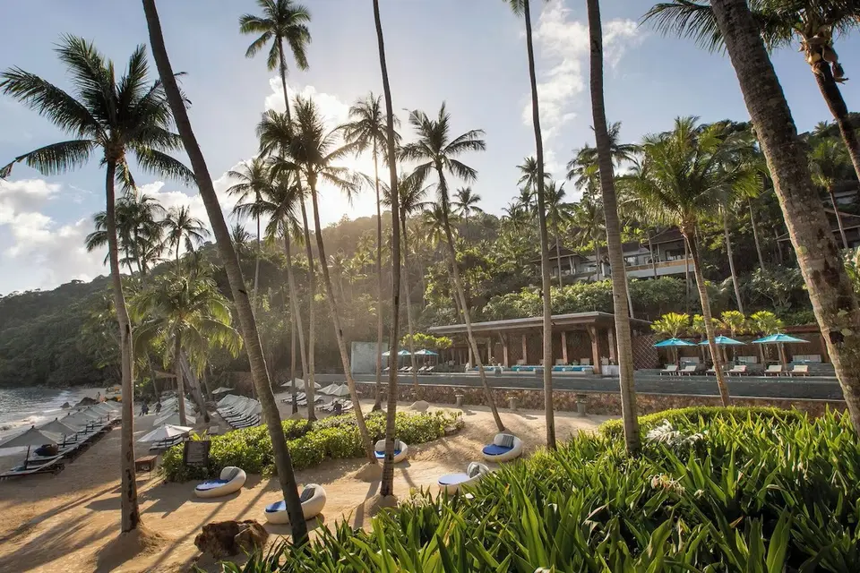 Solnedgang over palmeklædt strand og eksklusiv pool på Four Seasons Resort Koh Samui, hvor ro og luksus mødes.