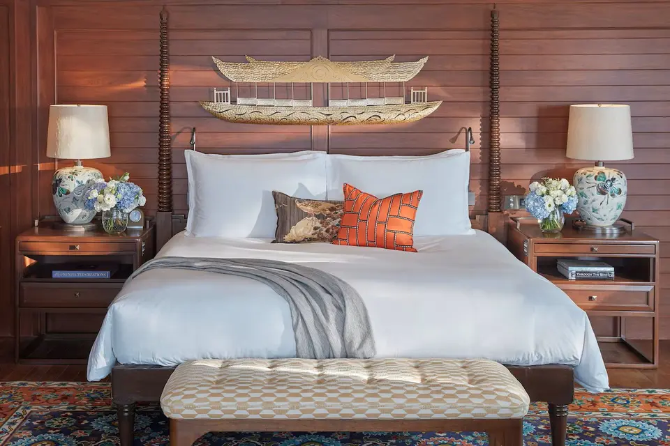 Elegant hotelværelse på Mandarin Oriental Bangkok med hvide linned, grå plaid og blomster ved siden af sengen.