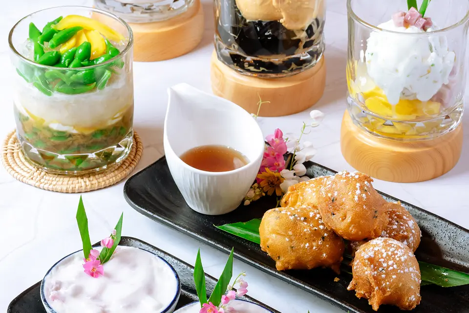 Dessertanretninger i glas og på fade med blomster som pynt.