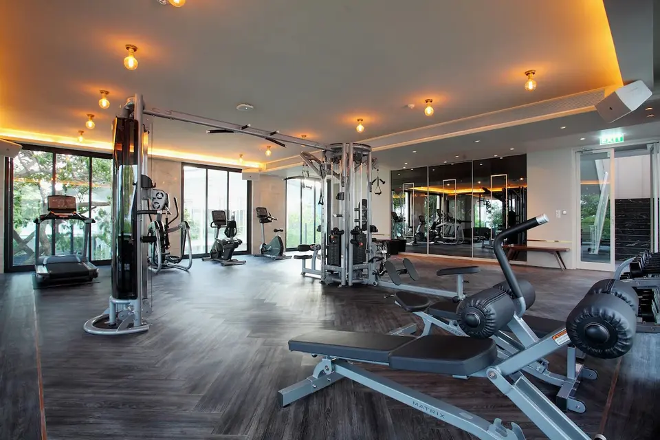 Fitnessrum med styrkemaskiner, træningsbænke og konditionsudstyr ved vinduerne.