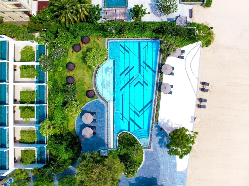 Elegant swimmingpool omgivet af grønne planter og liggestole på Baba Beach Club i Hua Hin, tæt ved strand og tropisk stemning.