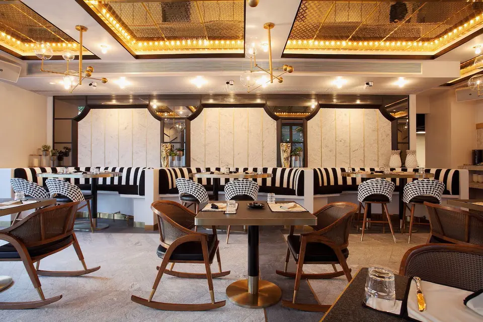 Restaurant med dækkede borde, gyngestole og sort-hvide stribede siddepladser.