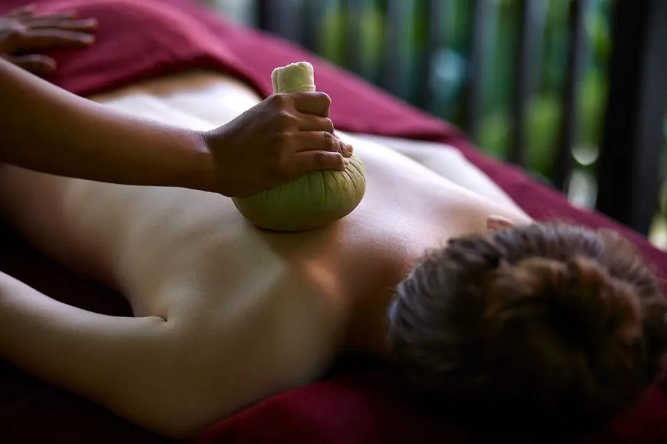 Massagebehandling med en stofindpakket kompres på ryggen.
