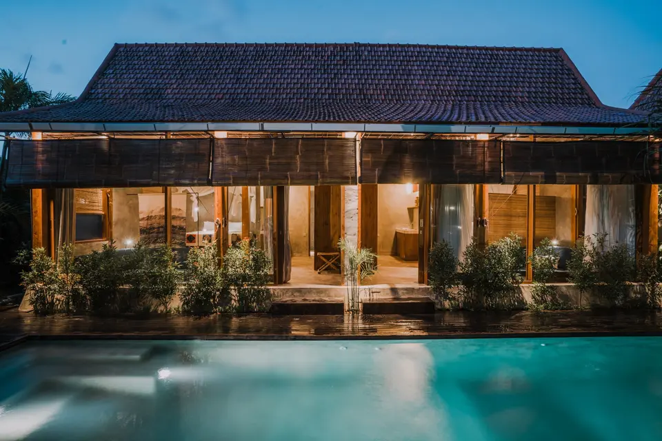Belyst villa ved en pool på ZIN Canggu i skumringen.