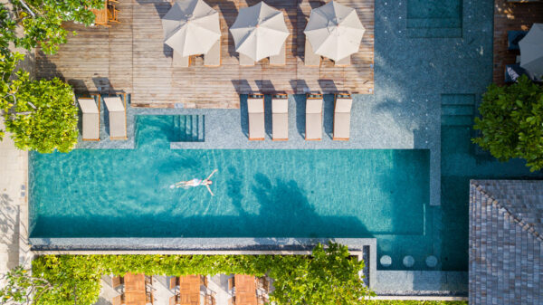 Overhead udsigt over Banana Fan Sea Resort swimmingpool omgivet af frodige grønne områder og liggestole.