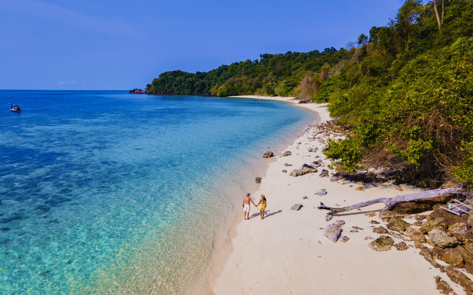 To mennesker slentrer på en sandstrand i Thailand nær Koh Island og nyder den eksotiske natur og den rolige atmosfære.